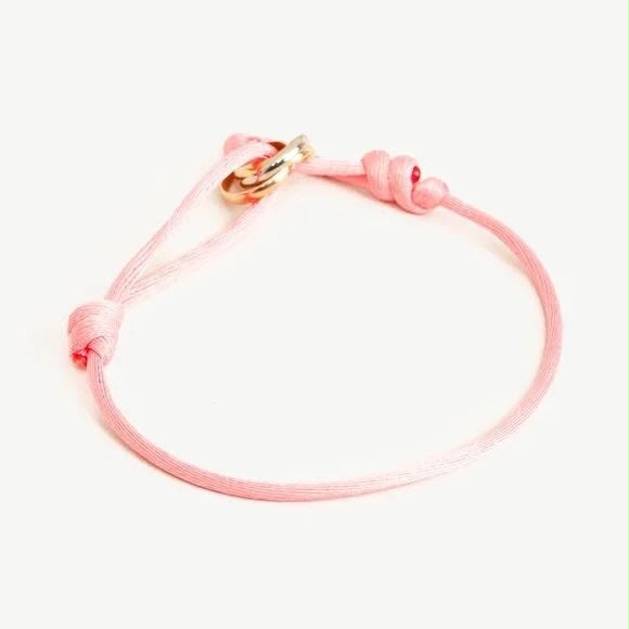 Pink cord bracelet with tri-colour rolling ring charm